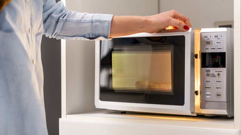 A woman's hands closing microwave oven door