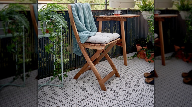 Plants surround a small wooden table and chairs sitting on a patio covered in ALTAPPEN Deck Tiles
