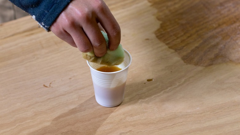 Person spreading oil on wood with a sponge