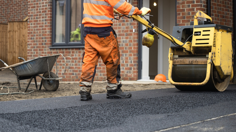 Worker rolling out an asphalt driveway