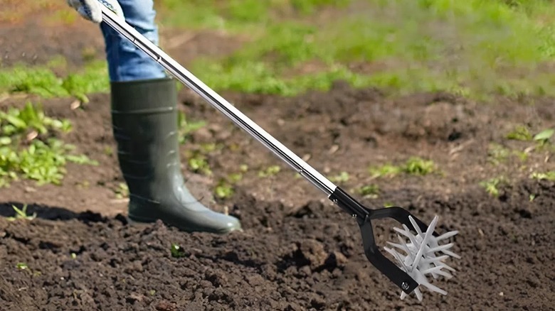 Person using the BARAYSTUS Rotary Cultivator/Aerator in a garden patch