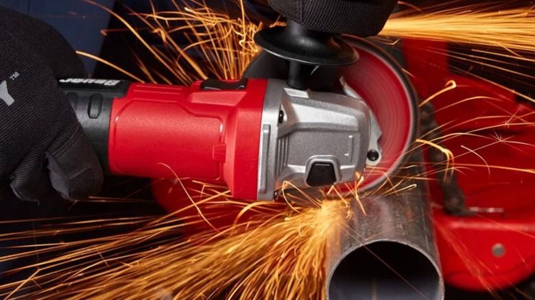 Angle grinder cutting through steel pipe. Sparks flying.