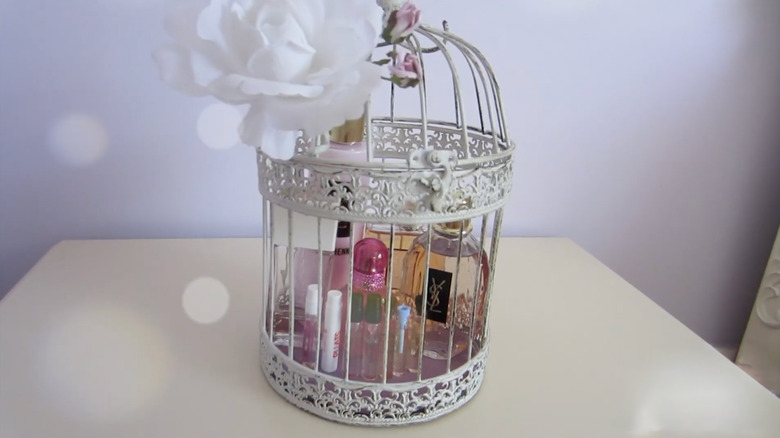 Perfume bottles are stored in a vintage white birdcage