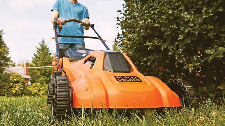 A man mower his lawn with the Black and Decker's BEMW213 corded electric push mower