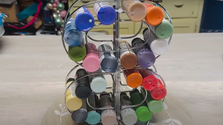 A circular stand made from paper towel holder and napkin holders with various colored craft paint in them.