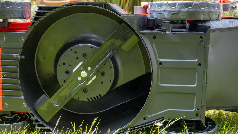A lawn mower turned on its side to reveal blade underneath.