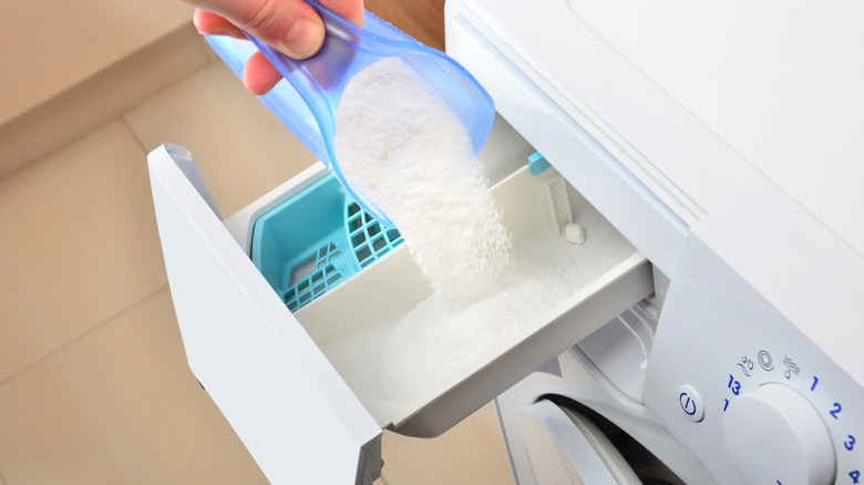 Hand adding in powdered detergent to a washer's dispenser
