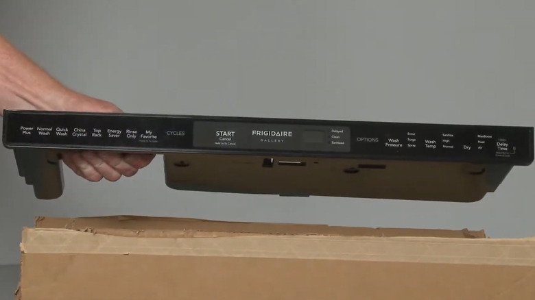 hand holding control panel for a Frigidaire dishwasher over a cardboard box