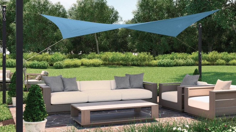 A blue Coolaroo shade sail is installed over an outdoor patio furniture set