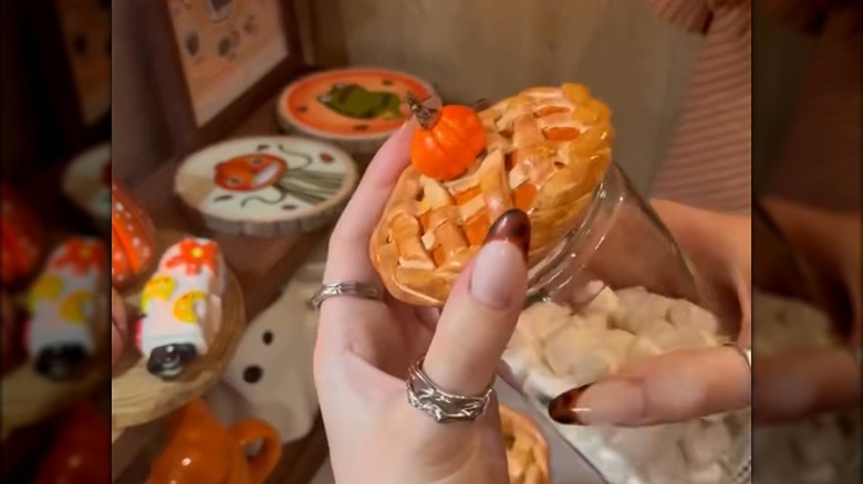 Creator holding a jar with a clay pie topper