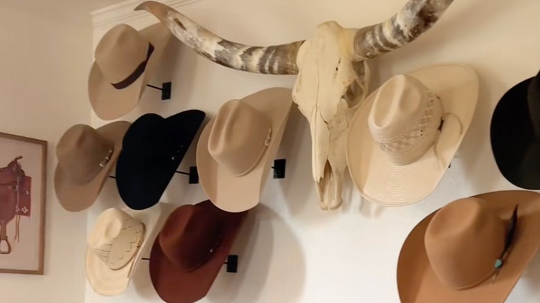 Vintage cowboy hats are displayed on a wall flanking a mounted longhorn skull