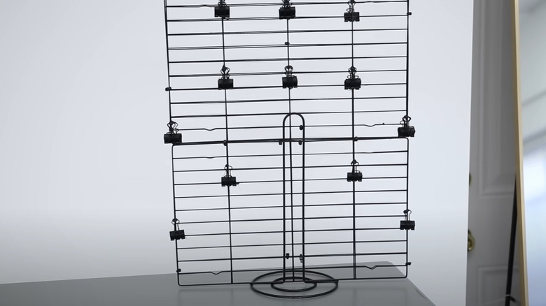 A black picture stand made from cooling racks and a paper towel holder.