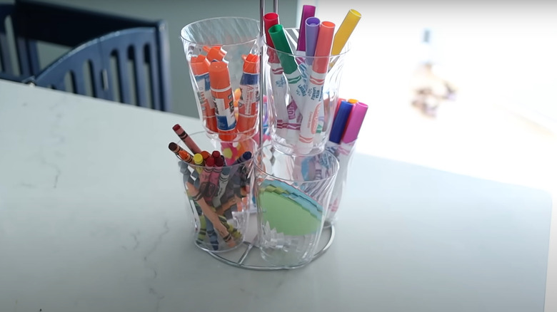 A tower of craft materials sitting on a kitchen island fashioned from a paper towel holder and some plastic cups.