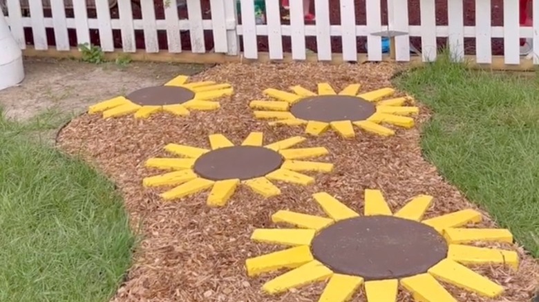 Painted concrete pavers are arranged to create a sunflower-shaped garden path