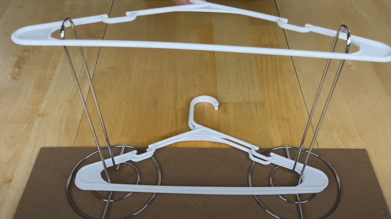White plastic hangers placed in a DIY hanger holder.