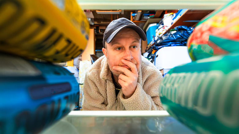 Man selecting a beverage from a garage refrigerator