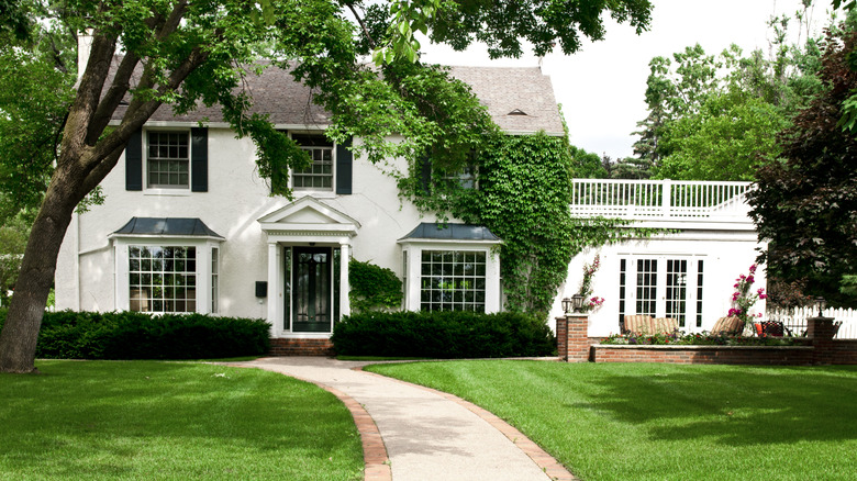 Dutch colonial style home surrounded by trees