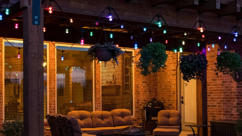 Colorful decorative lights hang from a patio ceiling above a set of outdoor furniture
