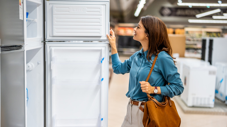 A woman checks out a top-freezer refrigerator model at an appliance store.