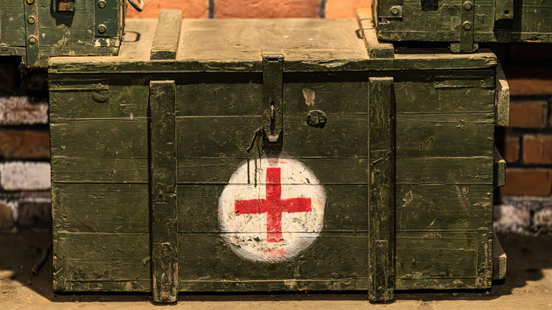 An old painted first aid chest sits on the ground of a thrift store
