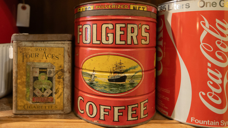 A vintage Folgers's Coffee tin on a shelf with other tins