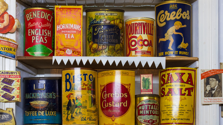A variety of colorful vintage tins are displayed on white shelves
