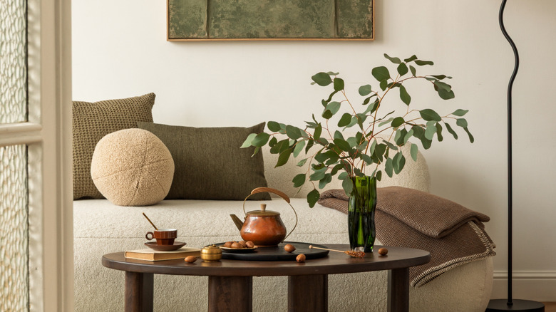 Modern living room with a tall asymmetrical arrangement of greenery in a vase on the coffee table