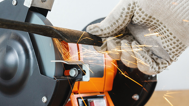 A gloved hand sharpening a blade