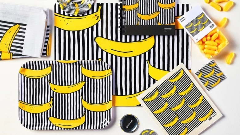 A large black and white striped tea towel overlaid with graphic yellow bananas is shown in a detail shot