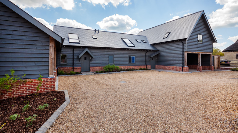A dark house with a pea gravel driveway