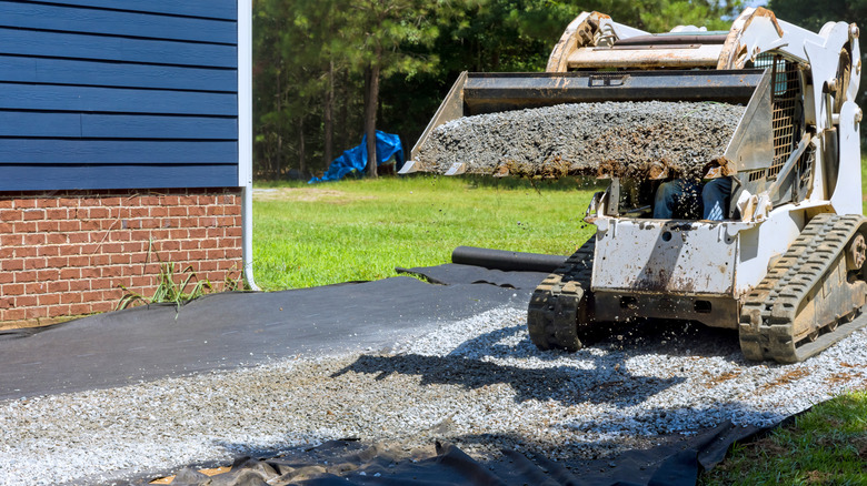 A skid steer pouring a gravel driveway