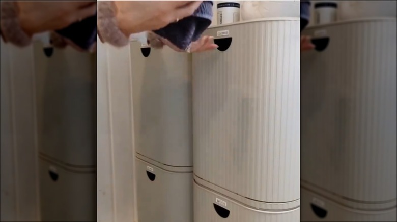A woman puts laundry into IKEA GÅRDSBUTIK bins