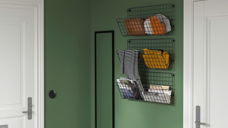 Three checkered black GREJIG wall pockets hanging on a green wall