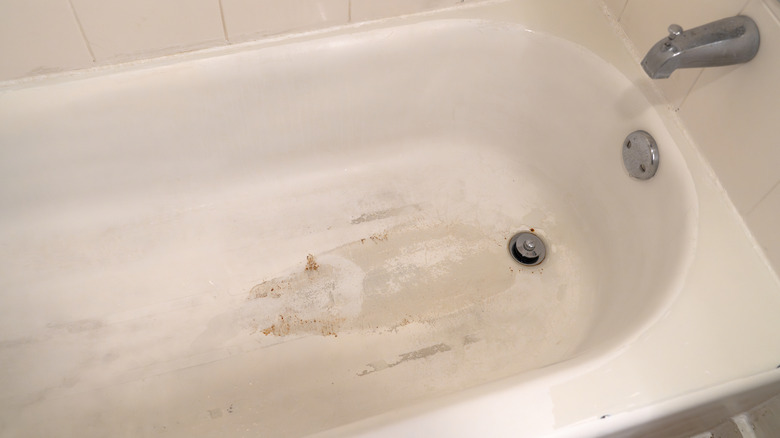Brown stains on a white bathtub in a bathroom