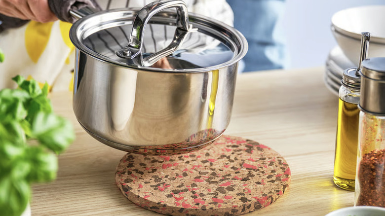 Person placing a hot pan on a colorful HEAT trivet