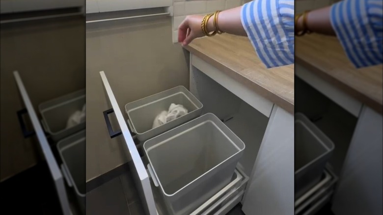 A woman throws laundry into IKEA HÅLLBAR bins.