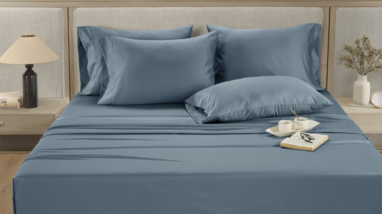 Hotel Signature blue sheets on a bed with tan wooden furniture