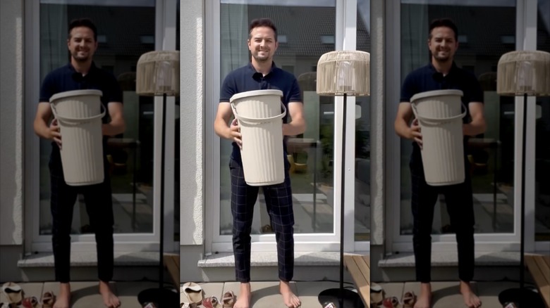 a man outside holding a bin with many shoes at his feet