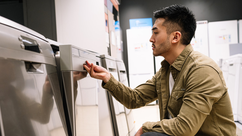 Man examining dishwashers in a store