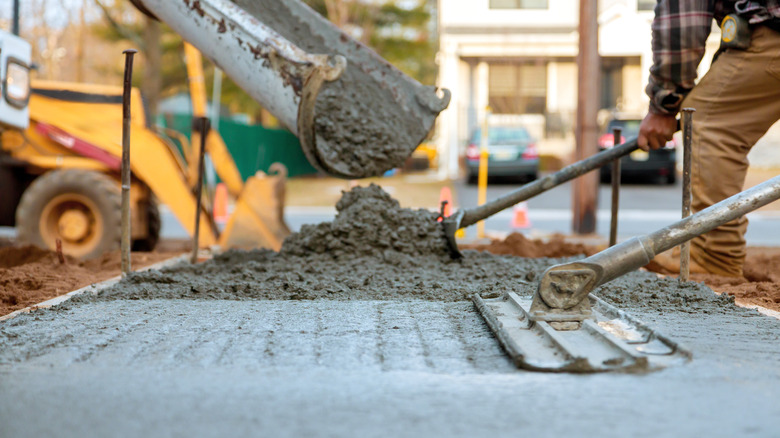 Workers pouring and leveling concrete mix