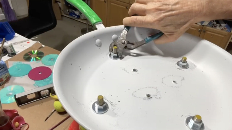 hand attaching bolt to frying pan planter