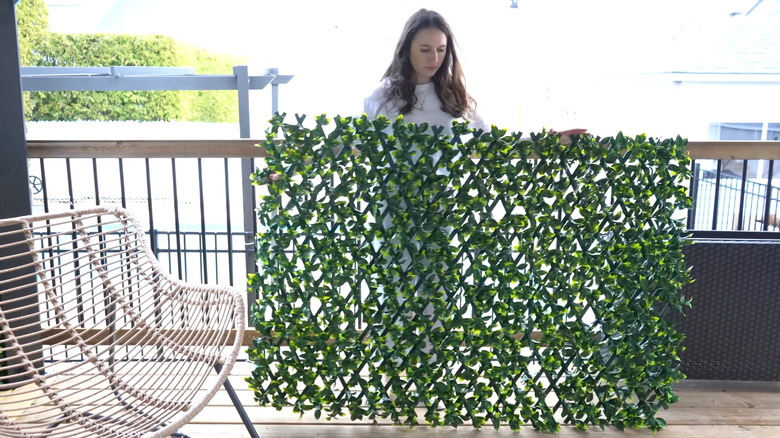 Woman adjusting an expandable lattice fence with faux vines