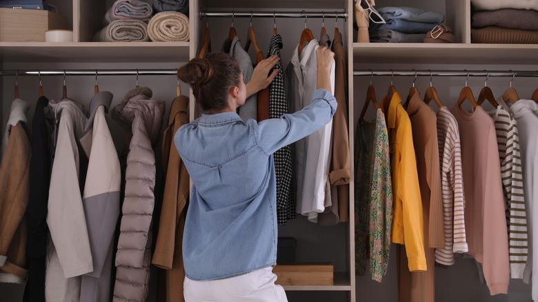 Woman sifting through a closet with neatly hanging clothes