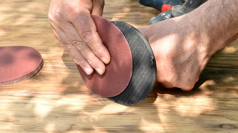 Person putting a disc on a drill sanding attachment