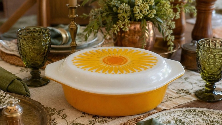 A Pyrex Golden Sunflower Daisy casserole dish sits on a dining table