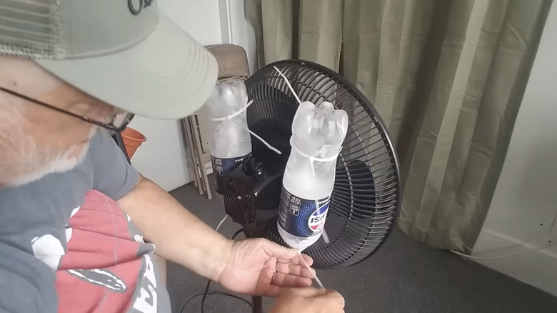 man tying frozen Pepsi bottles onto fan