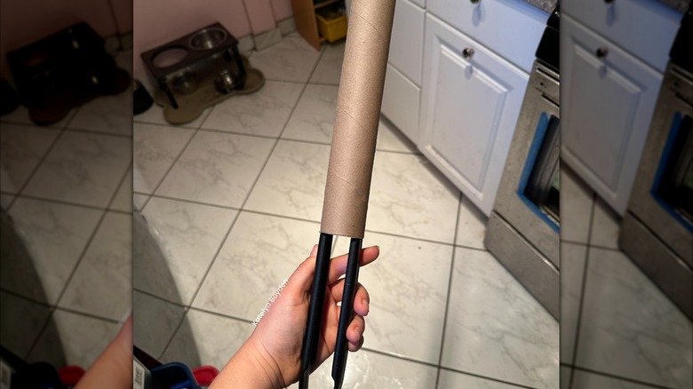 A pair of kitchen tongs slipped into an empty paper towel roll
