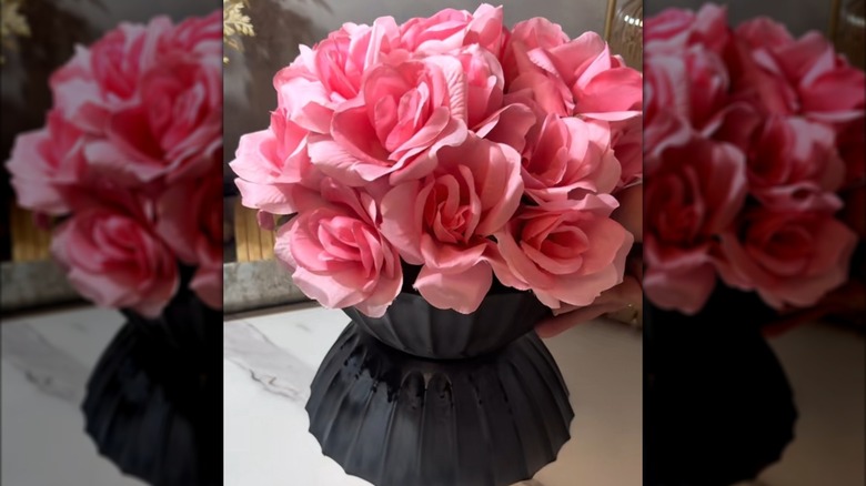 A black planter filled with pink roses