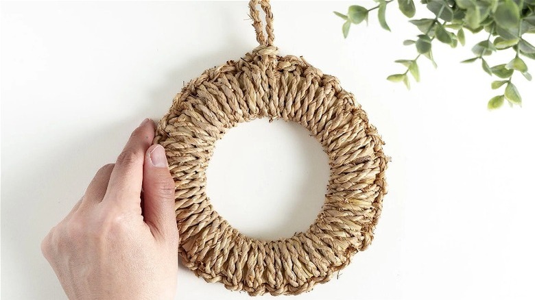 Person putting a straw Japanese trivet on a wall to hang as decoration