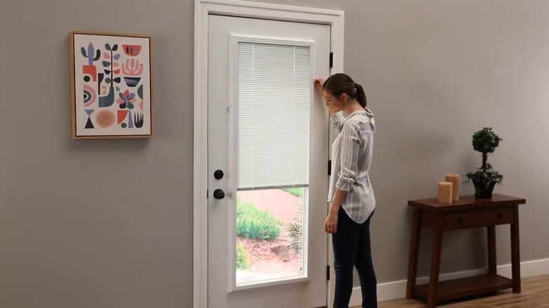 Woman lowering add-on blinds to cover the glass on a door
